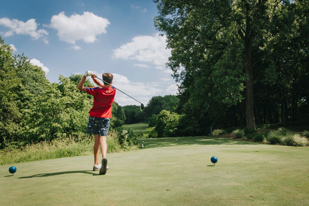 Youth golfer hitting tee shot from tee box