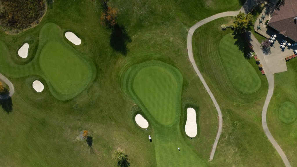 Aerial view of three greens and clubhouse